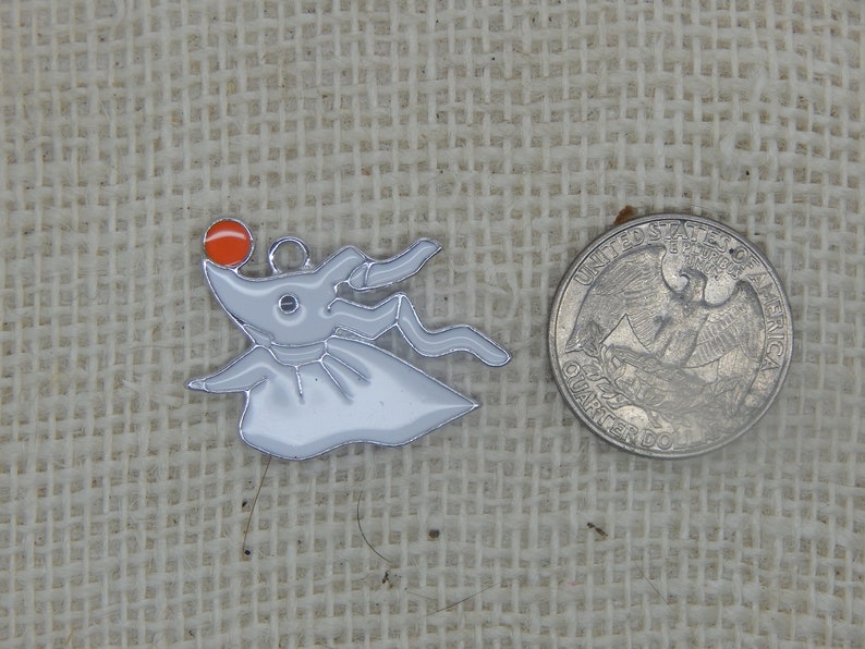 May include: A silver charm featuring a white ghost with a red nose and a black eye. The charm is about the size of a US quarter.