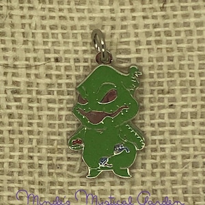 May include: Green and purple enamel charm of a character from the movie The Nightmare Before Christmas. The character is holding a small red heart and a blue and white striped bag.