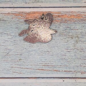 May include: A silver glitter witch charm with a loop for hanging.