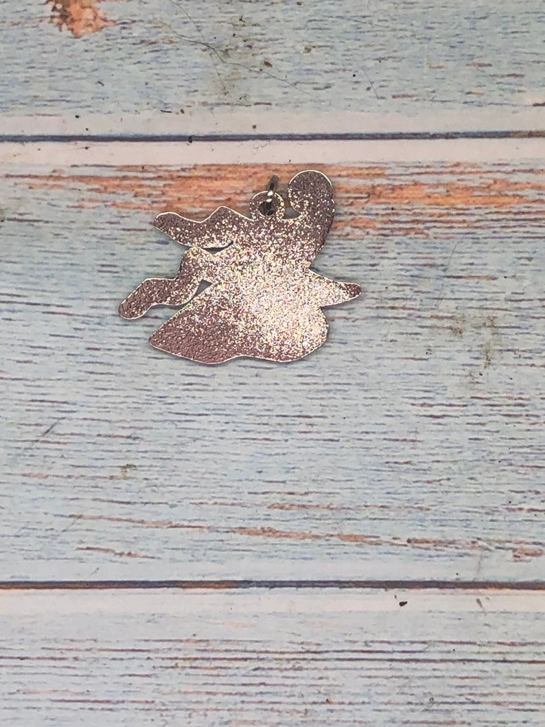 May include: A silver glitter witch charm with a loop for hanging.