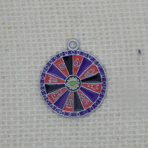 May include: A silver charm in the shape of a wheel of fortune with purple, red, and black sections. Each section has a different symbol in white.