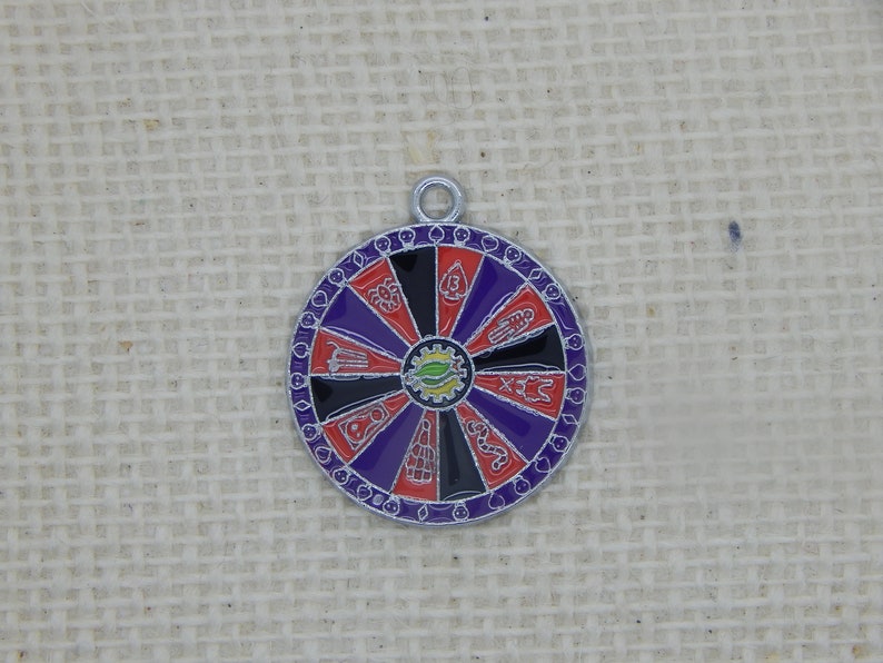 May include: A silver charm in the shape of a wheel of fortune with purple, red, and black sections. Each section has a different symbol in white.