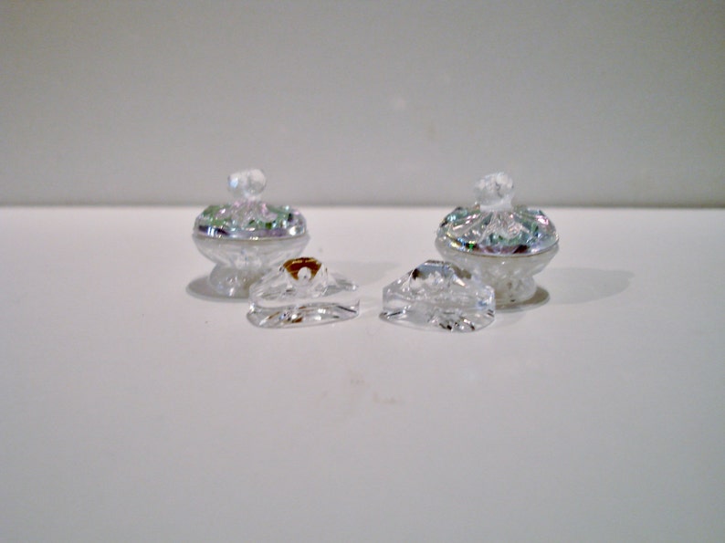 Peut inclure: Deux bols d&eacute;coratifs en verre transparent avec des accents iris&eacute;s et des couvercles assortis. Les couvercles sont s&eacute;par&eacute;s et pr&eacute;sentent un motif en relief.