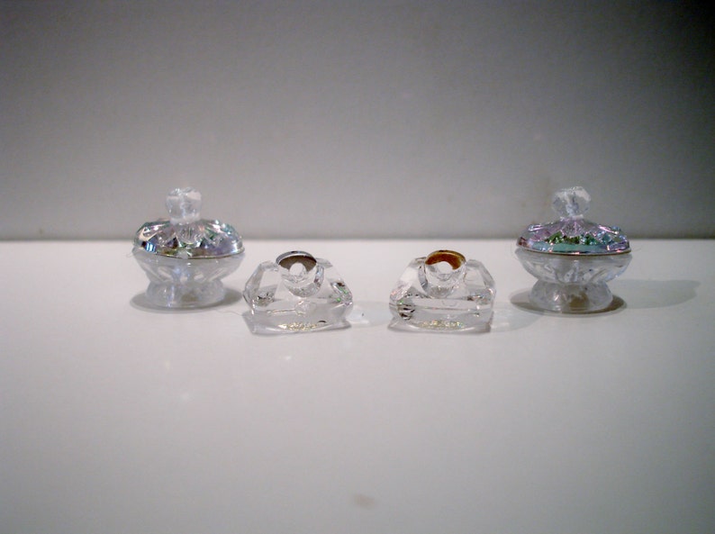 Peut inclure: Quatre contenants d&eacute;coratifs en verre transparent avec des dessus iris&eacute;s. Deux des contenants sont plus hauts et ont une base plus large, tandis que les deux autres sont plus courts et ont une base carr&eacute;e.