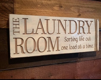 May include: White wooden sign with the text "The Laundry Room" and the phrase "Sorting life out one load at a time."