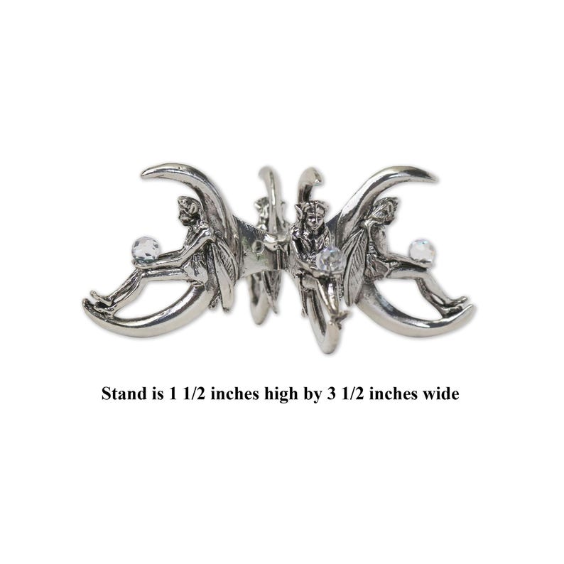 Puede incluir: Pinza de pelo de metal plateado con tres figuras de hadas. Cada hada sostiene una bola de cristal transparente. La pinza mide 3,8 cm de alto por 8,9 cm de ancho.