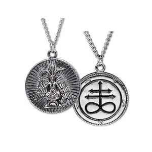 May include: Two silver-colored pendant necklaces. One pendant features a detailed image of Baphomet with wings, seated within a sunburst design. The other pendant displays the Leviathan Cross symbol. Both pendants hang from a silver chain.