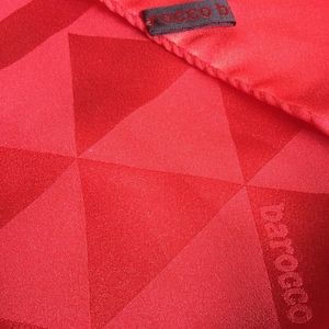 May include: A red silk scarf with a geometric pattern and the word "barocco" printed on it. The scarf has a small label that says "rocco b".