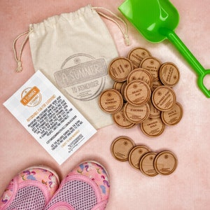 May include: A set of wooden tokens with summer activities printed on them, such as "Beach Day", "Giant Bubbles", and "Plant a Tree". The tokens are in a white drawstring bag with a green plastic shovel and pink water shoes.