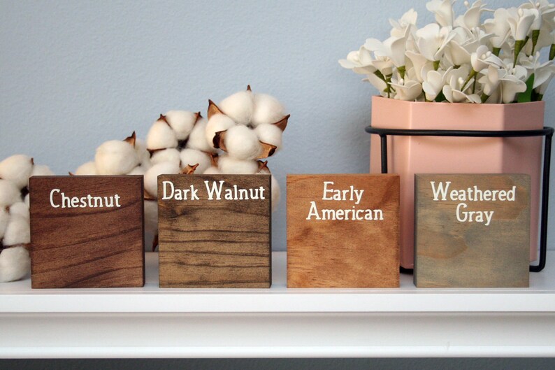 Puede incluir: Cuatro bloques de madera te&ntilde;idos en diferentes colores: Casta&ntilde;o, Nogal oscuro, Americano antiguo y Gris desgastado. Los bloques est&aacute;n dispuestos en una fila sobre un estante blanco.