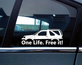 May include: A white vinyl decal applied to a car window, featuring a silhouette outline of a two-door SUV and the text "One Life. Free it!" in a bold, sans-serif font positioned directly below the vehicle graphic.