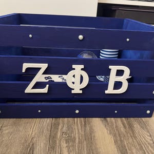 May include: A blue wooden crate with white letters spelling "ZPB" on the front. The crate is decorated with silver studs.