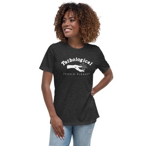 May include: A dark heather grey t-shirt with a white graphic of a hand reaching out with the text "Pathological People Pleaser" in a white retro font.