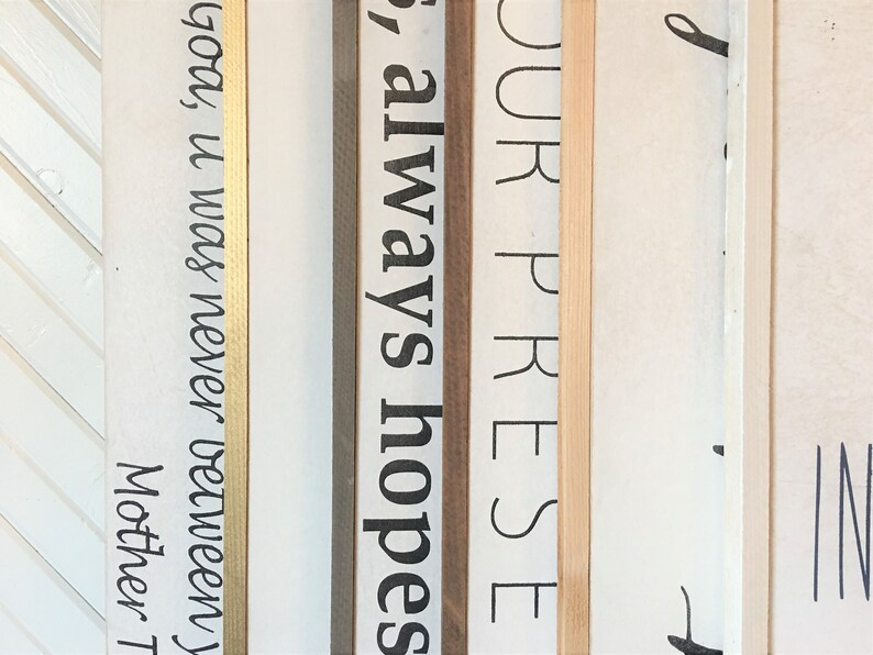 May include: Close-up of four wooden signs with gold, brown, and natural wood frames. The signs have the following text: "God, it was never between", "always hopes", "your prese", and "d".