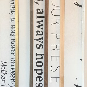 May include: Close-up of four wooden signs with gold, brown, and natural wood frames. The signs have the following text: "God, it was never between", "always hopes", "YOUR PRESE", and "d".