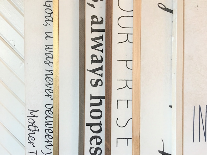 May include: Close-up of four wooden signs with gold, brown, and natural wood frames. The signs have the following text: "God, it was never between", "always hopes", "YOUR PRESE", and "d".