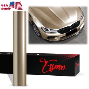 May include: A cylindrical roll of metallic champagne-colored vinyl wrap film standing vertically next to a black rectangular box labeled with the red text Essmo. Above the box, a luxury sedan is shown with a matching champagne-colored car wrap.