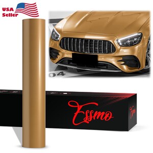 May include: A roll of metallic gold vinyl wrap stands next to a gold car. The roll is cylindrical and reflects light. The car has a black grill and headlights. A black box with the red word "Essmo" is at the bottom, and the American flag is in the top left.