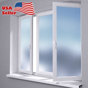 May include: A white window with three panes of glass. Each pane has a frosted film with a diagonal pattern. The window is open and the blinds are closed.