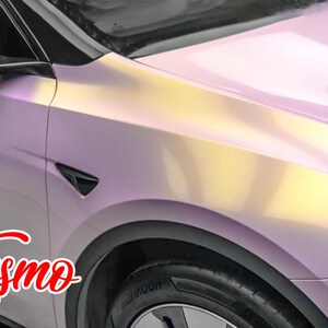 May include: A close-up of a pink and yellow car with a black side mirror and a black wheel. The car has a custom paint job with a gradient effect. The word "Essmo" is written in red cursive on the side of the car.