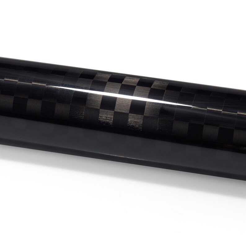 May include: A cylindrical rod featuring a glossy black and dark gray checkered carbon fiber pattern. The surface has a reflective finish with a distinct horizontal light highlight running across the length of the tube, showcasing the weave.