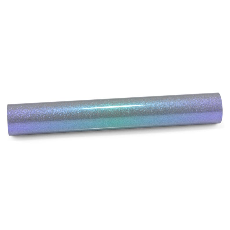 May include: A cylindrical roll of craft vinyl featuring a smooth, glittery finish that transitions between shades of iridescent purple, blue, and teal. The surface has a fine, reflective texture that catches the light, creating a gradient effect.