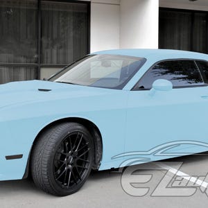 May include: A light blue two-door coupe car featuring a matte finish, black multi-spoke alloy wheels, tinted windows, and a rear spoiler. The vehicle has a low-profile stance with a prominent front grille and a watermark logo in the bottom right corner.