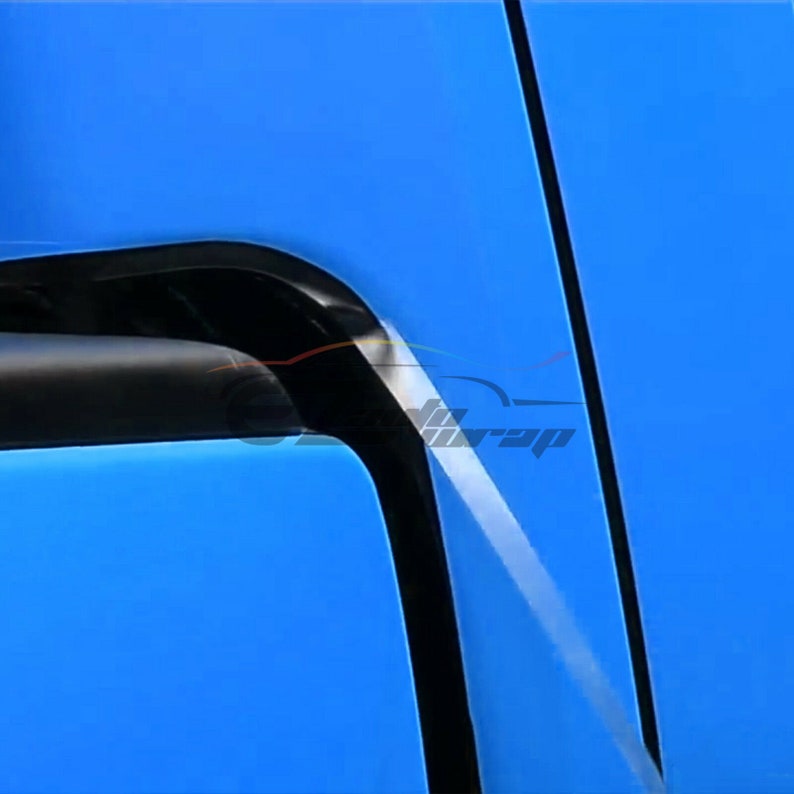 May include: A close-up of a blue car door with a black trim. The door has a slight curve to it and the trim is visible along the edge.