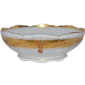 May include: A white porcelain bowl with a gold and brown floral design. The bowl has a scalloped edge and a raised base.