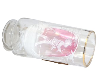May include: A clear glass bottle with a gold rim and a pink and white etched design of a figure holding a flower.