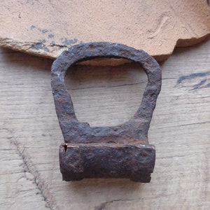 May include: A rusty metal padlock with a D-shaped shackle and a rectangular body. The padlock is missing a keyhole.