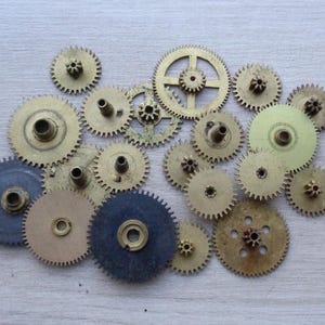 Op de afbeelding: Een verzameling van goudkleurige metalen tandwielen in verschillende maten en vormen, gerangschikt op een licht houten oppervlak.