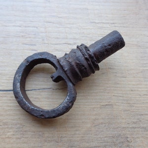 May include: A rusty metal key with a circular handle. The key is old and has a worn finish.