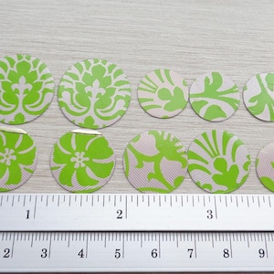 Könnte beinhalten: Neun grüne und weiße Papierkreise mit jeweils unterschiedlichen Mustern sind auf einer Holzoberfläche angeordnet. Unter den Kreisen befindet sich ein Lineal mit den Zahlen 1 bis 4.