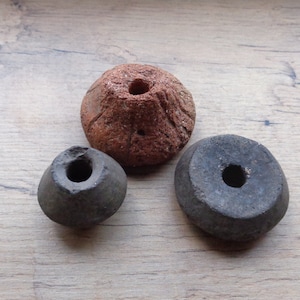 Peut inclure: Trois perles en céramique avec des trous au centre. Les perles sont de tailles et de couleurs différentes. Une perle est brune, une est noire et une est grise.