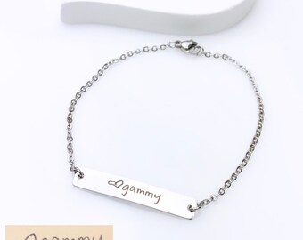 May include: A silver chain bracelet with a bar charm engraved with the handwritten text "gammy" with a heart symbol.