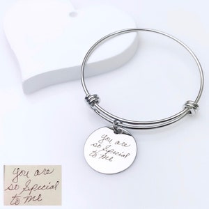 May include: Silver bangle bracelet with a round charm that says "You are so special to me" in handwritten script.