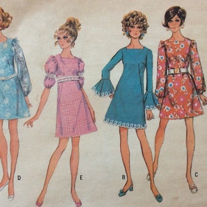 May include: Five different dress patterns with illustrations of women wearing the dresses. The dresses are in various colors and patterns, including brown, blue, pink, and floral. The patterns are labeled A, B, C, D, and E.