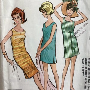 May include: Vintage sewing pattern featuring illustrations of three dresses. The dresses are in various styles, including a striped green and white dress with a giraffe design, a yellow and orange striped dress, and a teal dress. The pattern is labeled "Quickie Pattern."