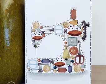 May include: A white card with a sewing machine design made up of various sewing supplies, including buttons, needles, thread spools, and scissors. The card has a dashed line border.