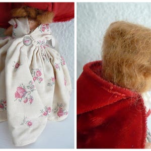 Puede incluir: Una mu&ntilde;eca vintage que lleva un vestido blanco con estampado floral y una capa de terciopelo rojo. La mu&ntilde;eca tiene el pelo largo y casta&ntilde;o.