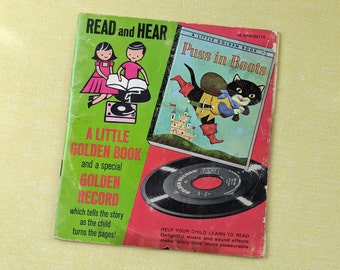 May include: A Little Golden Book with a record titled "Puss in Boots". The book features illustrations of children reading and a cat in boots.