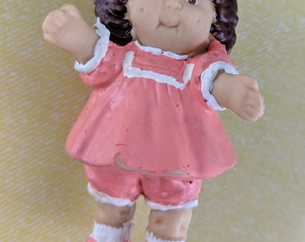 Figura infantil Cabbage Patch Morena con vestido rosa