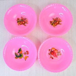 May include: A set of four round, bright pink bowls with scalloped edges. Each bowl features a unique, colorful decal at the center, including illustrations of various fruits, green leaves, and a small yellow butterfly on one of the bowls.