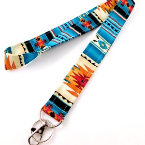 May include: A blue, orange, and white patterned lanyard with a silver swivel clip. The lanyard has a geometric design.