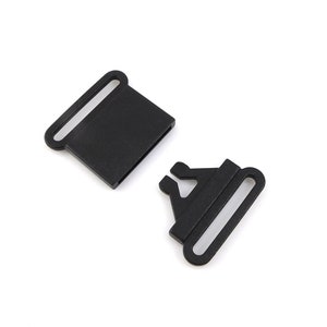 May include: Two black plastic slider buckles for straps or belts. The buckles are designed to be used with webbing or straps.