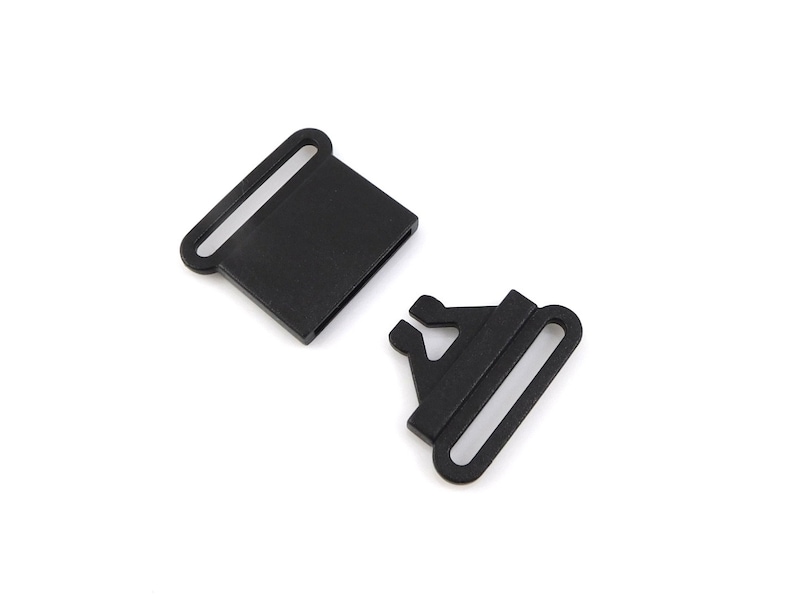 May include: Two black plastic slider buckles for straps or belts. The buckles are designed to be used with webbing or straps.