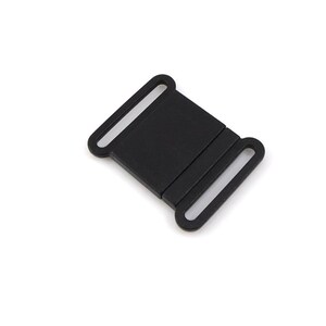 May include: Black plastic buckle with two loops. The buckle is designed to be used with a strap or webbing.
