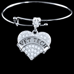 May include: A silver expandable bracelet with a heart-shaped charm that says "VET TECH" in black lettering and is covered in clear rhinestones.