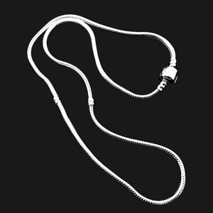 Puede incluir: Un collar de cadena de serpiente en tono plateado con una estructura de eslabones lisos y flexibles. La cadena incluye un dije de cuenta cil&iacute;ndrica de metal posicionado a lo largo del hilo y dos peque&ntilde;os topes met&aacute;licos fijos para asegurar el dije.
